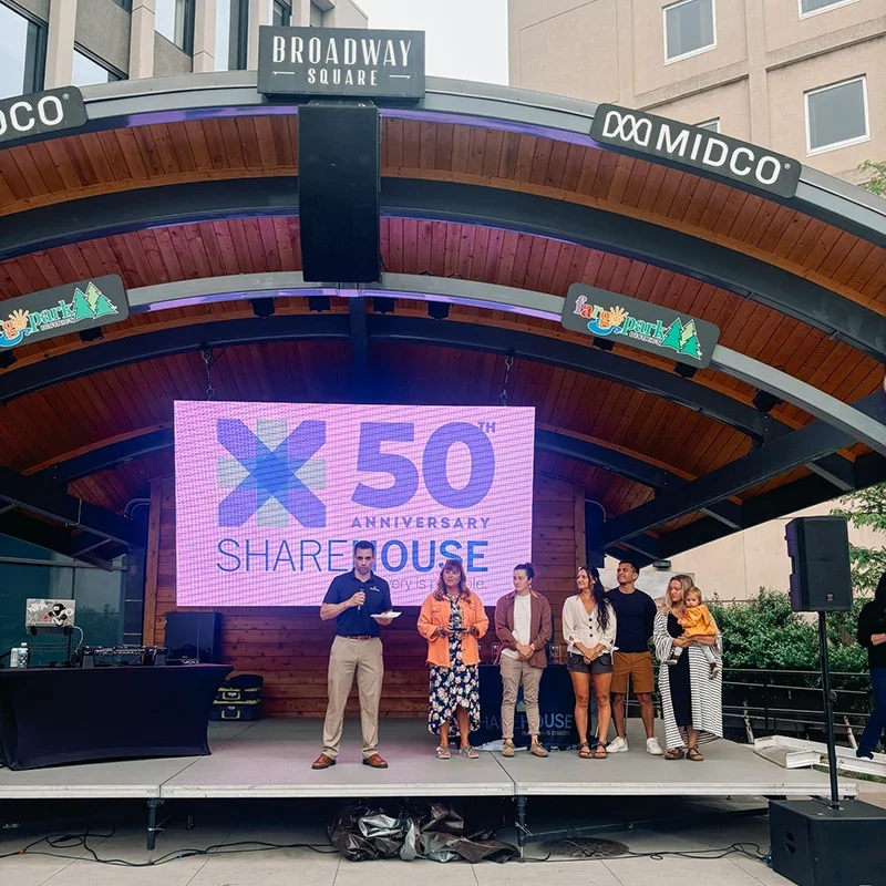 Sharehouse team and guests on stage speaking at 50th anniversary event