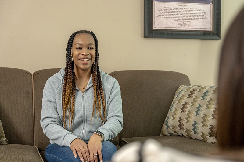 Young woman smiling and speaking with ShareHouse counselor in office
