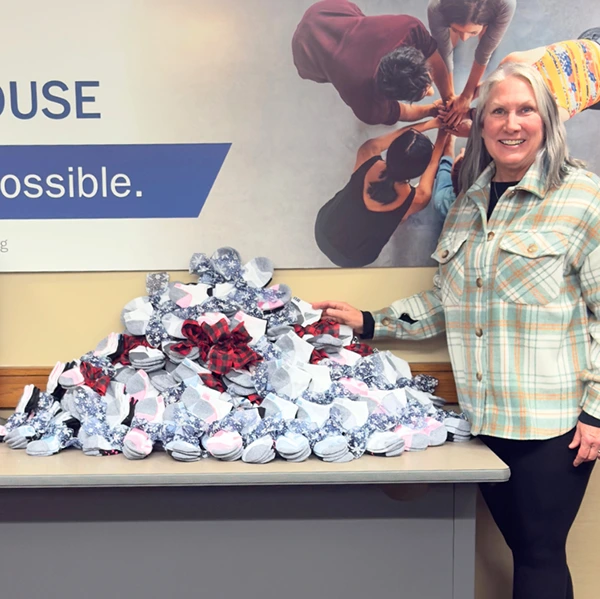Sharehouse team member smiling next to pile of donated essential socks from Amazon wishlist