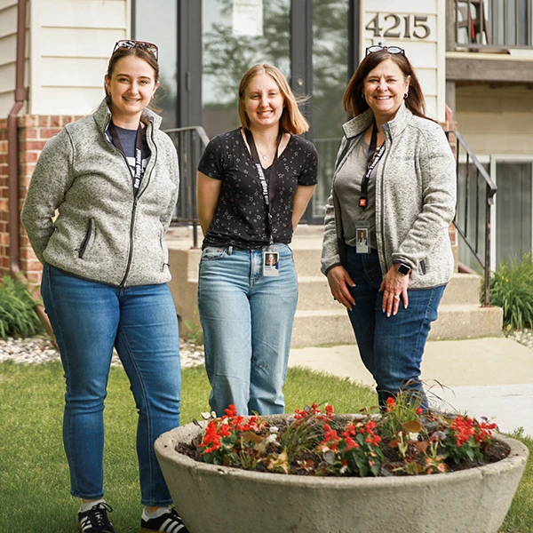 Volunteers smiling after planting flowers in front of ShareHouse Residential building